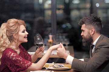 Young couple at restaurant having dinner. Man and woman rest in restaurant. People drink in club. Lovers sit in cafe bar, date meeting in pub.
