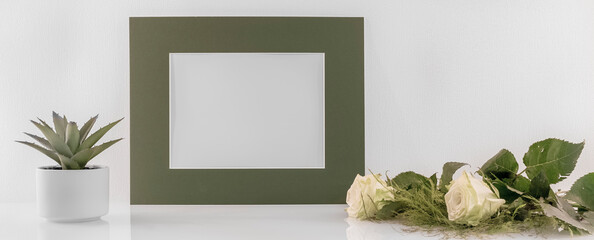 Modèle de cadre photo blanc avec espace vide pour logos, inscription publicitaire. Cadre en mode paysage sur un espace de travail avec des roses. Ambiance zen.