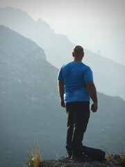 Hiker in a blue shirt and black pants, with his back turned, contemplating a beautiful landscape at...