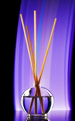 incense sticks in a jar of oil filmed with artificial decorative light