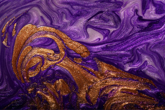Beautiful purple and gold stains of liquid nail polish,fluid art technique.Shimmer marble background.Liquid stripy paint texture.Nail laquer flow modern backdrop.Minimalistic concept.Copy space.