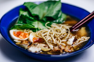 Ramen noodles with egg and bok choy in a cobalt blue bowl