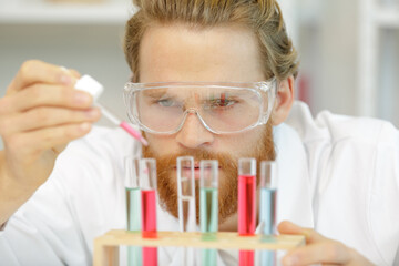 close view of male scientist dripping liquid into test-tube