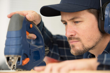 man cutting wood with a saw inside