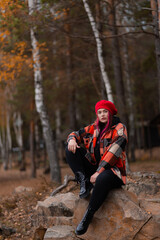 Confidently looking girl is sitting on a rock in an autumn forest.