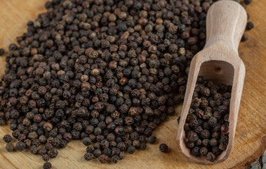 A wooden board with dried peppercorn on a gray background