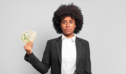 young afro businesswoman looking puzzled and confused, biting lip with a nervous gesture, not...