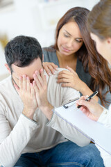 Woman comforting tearful man in therapy