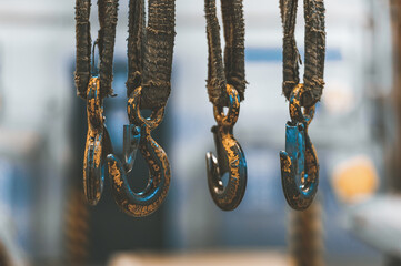 Old yellow frayed hooks of a mobile crane on a blurred background of industrial premises. © vadimalekcandr
