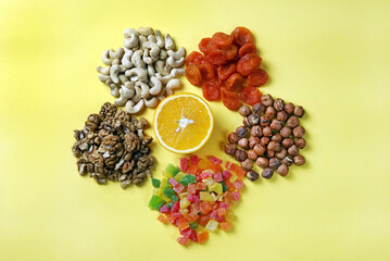 hazelnuts walnuts cashews and candied fruits with orange on a yellow background