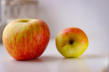 A few ripe apples on a white surface. Rear background is blurred