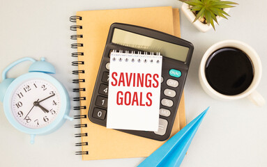 Office table with pen, cup coffee and empty paper with SAVINGS GOALS text