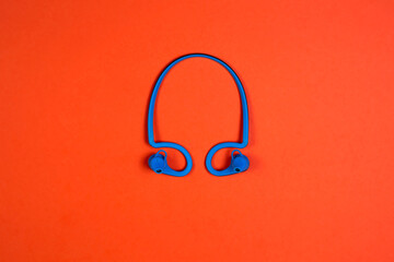 blue wireless headphones for listening to music on an orange background,