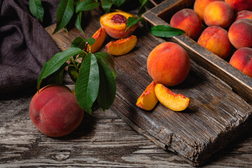 Naklejka na ściany i meble Still life peach dark key. Peach fruit harvest. Juicy ripe peaches on dark wooden rustic table. Delicious farm peaches with leaves whole fruit in halves, peach with bone