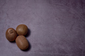 Group of three kiwis on stone floor