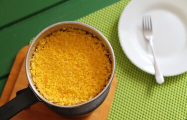 Couscous in the pan, with plate and fork in the background. Brazilian Couscous (cuscuz brasileiro) ready to be served.