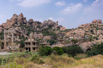 Chitradurga, Karnataka, India - November 10, 2013: Fort or Elusuttina Kote. Lots of visitors at Hidambeswara Temple ruinous buildings under blue sky with green foliage and boulders backdrop.