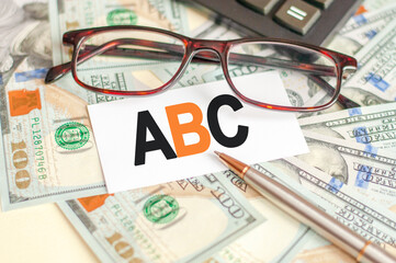 The letters A and B and C are written on a white card lying on the bills, glasses, pen and calculator in the background. The concept of business and Finance