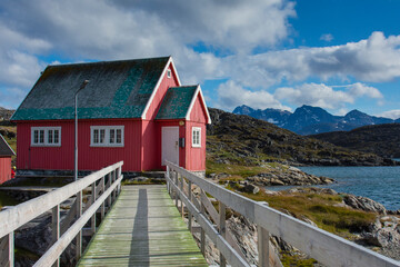 Greenland. Itilleq. Wooden bridge leading to a red house.