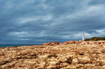 Island scenery with rocks and sea in gloomy weather, lighthouse