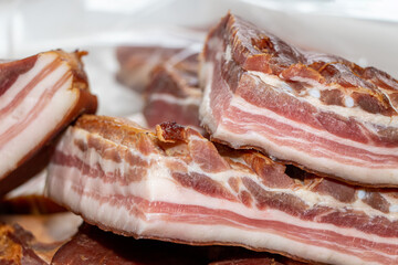 Obraz premium Smoked pork bacon on a wooden board with several cut pieces