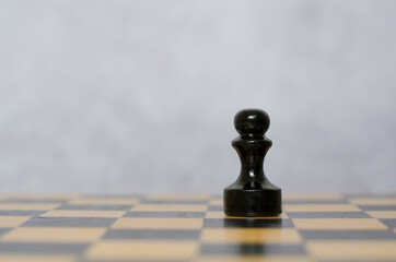 Wooden black pawn on a chessboard. Chess pieces, side view