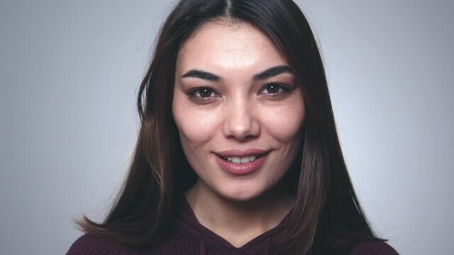 Happy brunette woman blinking eye, looking at camera with toothy smile, winking and flirting, expressing optimism.