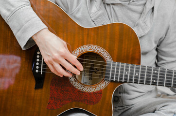 Woman musician plays the guitar. Fingers touch the strings close-up
