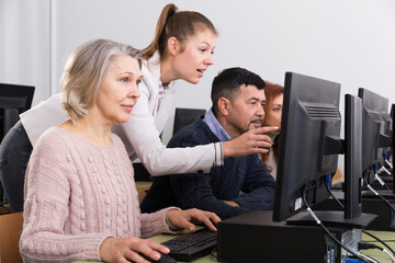 Serious businesswoman helping to man, pointing at computer monitor in office