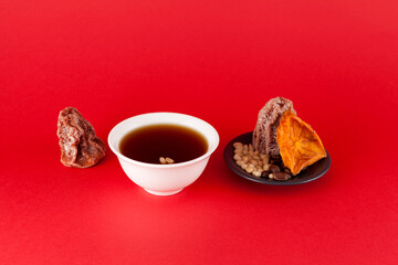 Sujeonggwa - Korean cold fruit tea or chilled punch red background with copy space. It is made from...