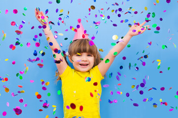 Obraz na płótnie Canvas happy child girl with confetti on blue background 