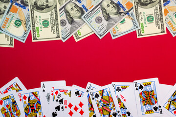 American dollars banknotes with playing cards on red background with copy space. Game addiction. Gambling, casino