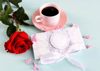 A delicate composition with red rose and cup of coffee with a postcard