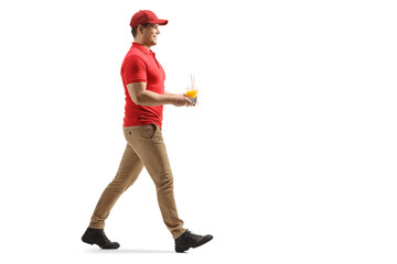 Full length profile shot of a delivery guy walking with a cup of fresh orange juice