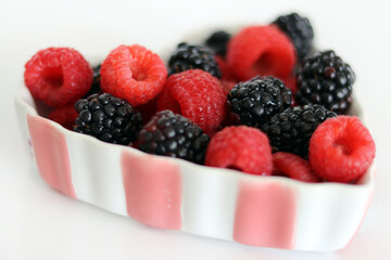 Red Raspberries and Blackberries in a Pink and White Bowl with White Background.