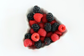 Red Raspberries and Blackberries in a Pink and White Bowl with White Background.
