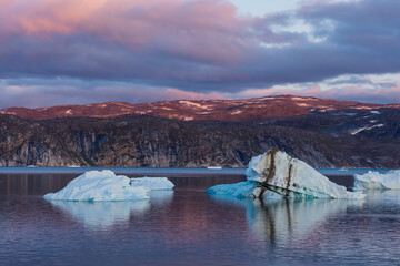 Greenland. Disko Bay. Sunset with icebergs and the arid coast of Greenland.