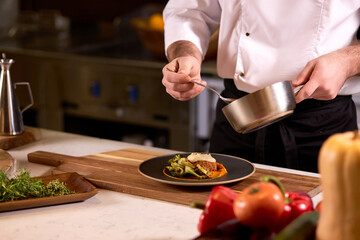 chef dressing salad with sauce, pouring sauce into plate, finishing cooking of meal in restaurant...