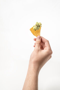 hand holding a tortilla chip with guacamole 