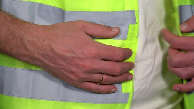 Closeup view 4k stock video footage of adult white man putting on bright green reflective vest or safety jacket