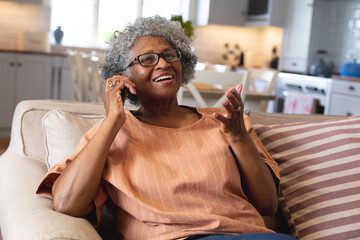 African american senior woman smiling while talking on smartphone at home