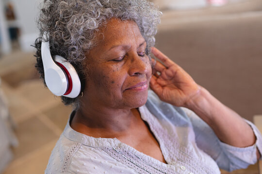 African american senior woman wearing headphones enjoying listening to music at home