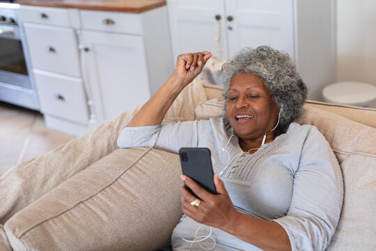 African american senior woman smiling while having a video call on smartphone at home - Powered by Adobe