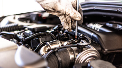 Auto Mechaniker repariert den Motor in der KFZ Autowerkstatt und wechselt das Motoröl des Motors - obrazy, fototapety, plakaty
