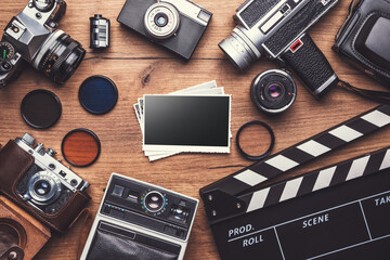 Vintage retro camera with clapboard and old photos on wooden background, clipping path