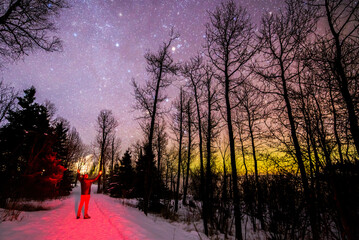 Man standing in front of northern lights in Minnesota forest during winter.  Inspirational motivational scene