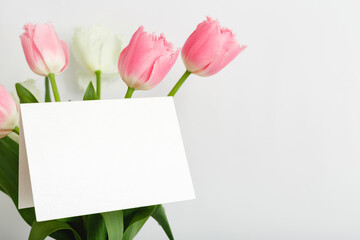 Flowers mock up congratulation. Congratulations card in bouquet of pink tulips on white background. White blank card with space for text, frame mockup. Spring festive flower concept, gift card.