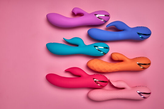 Bright Colorful G-spot Vibrators Arranged On Pink Paper Background, Big Variety Of Dildo Colours. Copy Space, Flat Lay