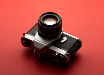 Old vintage retro SLR DSLR 35mm analog film camera body with lens on red background