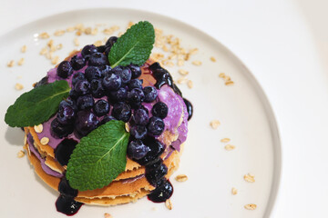 Blueberry pancakes with cream and jam close-up, selective focus. Tasty breakfast. Copy space, top view